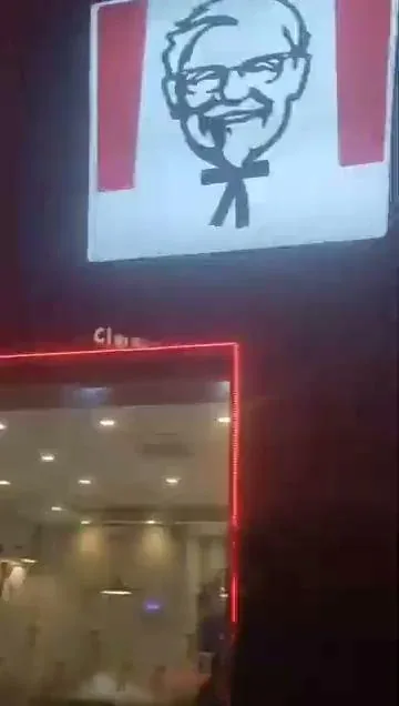 A lit-up KFC storefront sign outside a branch at night, one of the merchants a Novaluxia PH points voucher redeems at