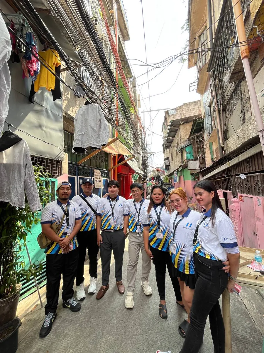 Field team in matching Novaluxia polo shirts walking a narrow residential street, a recruitment image in the middle of the is novaluxia legit debate